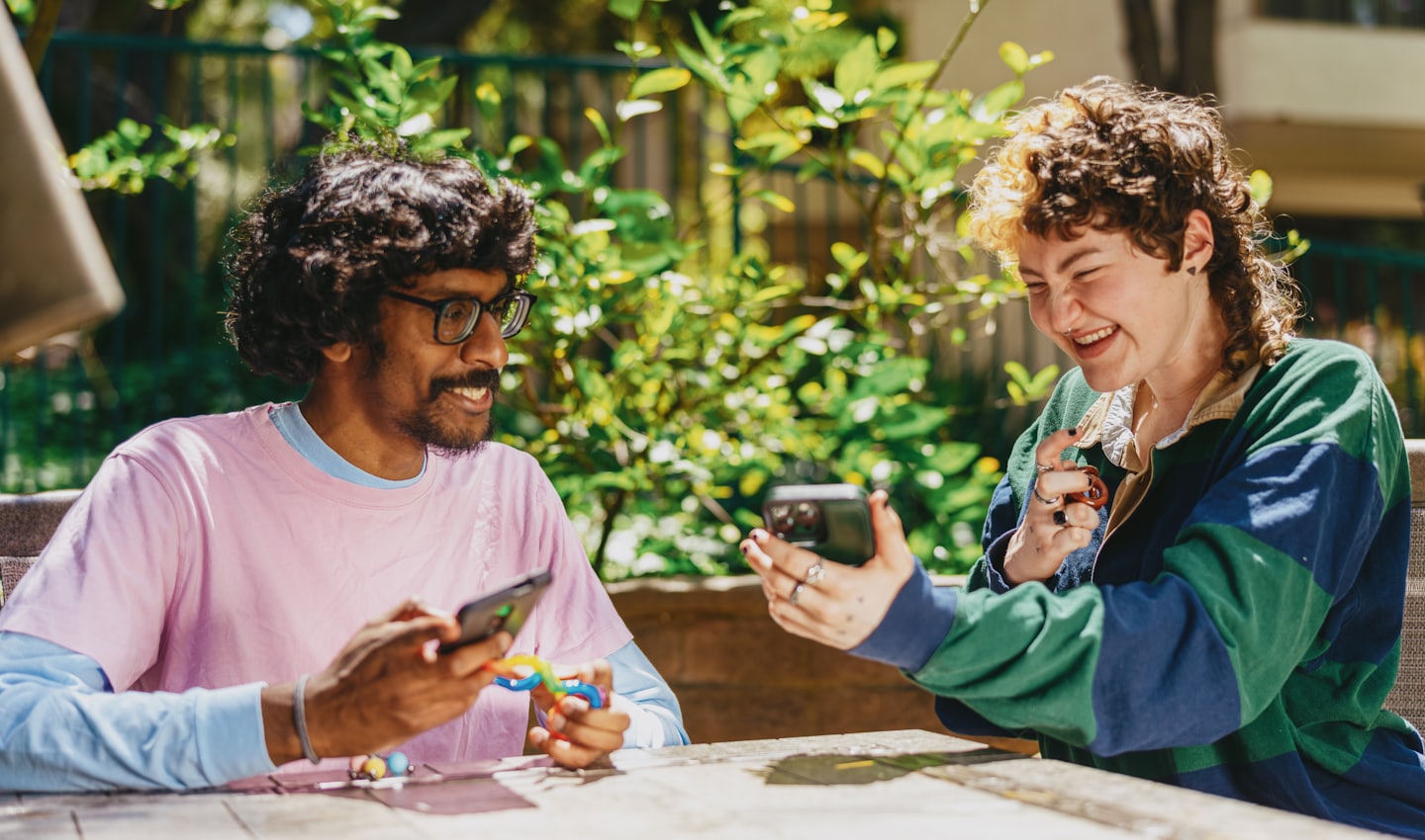 Two friends sitting outdoors and laughing